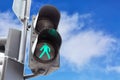 Traffic lights with the green light lit for pedestrians against blue sky background with clouds. Royalty Free Stock Photo
