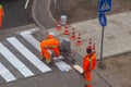 Traffic line painting. Workers are painting white street lines on pedestrian crossing. Road cones with orange and white Royalty Free Stock Photo
