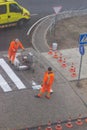 Traffic line painting. Workers are painting white street lines on pedestrian crossing. Road cones with orange and white Royalty Free Stock Photo