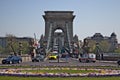 Traffic over the chain bridge linking the buda and pest side together. Flowers blooming on roundabout in spring.