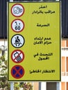 A traffic road sign in Arabic (traffic radar, maximum speed 60, seat belt, no cellphones, no parking) )