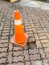 Traffic safety cone to warn missing paver bricks floor pathway. Selective focus.