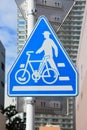 Traffic sign, blue pentagon pedestrian and bicycle sign on metal post with cityscapes background