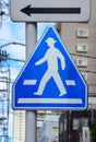 Traffic sign, blue pentagon pedestrian sign on metal post with cityscapes background