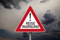 Traffic sign with covid-19 corona virus and the german translation for travel warning - Reisewarnung with dark cloudy sky