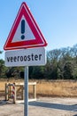 Traffic sign indicating caution with the inscription below that reads: cattle grid, green trees in the background Royalty Free Stock Photo