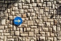 Traffic sign one way street sign with an arrow on a stone wall is a pattern of texture and material with colored stones. Royalty Free Stock Photo