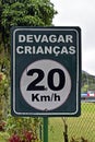 Traffic sign speed limit at 20 kilometers per hour with portuguese words that mean SLOWLY CHILDREN Royalty Free Stock Photo