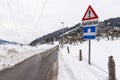 Red triangle road traffic warning sign - Other Danger with text Ausfahrten which means Exits. Snow covered road, trees and mountai