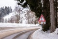 Red triangle road traffic warning sign - Other Danger. Crossroads with cross-country skis paths . Snow covered road, trees and mou Royalty Free Stock Photo