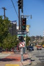 A traffic signal with green arrow, a one way sign, and a no left turn sign with cars, truck and buses driving on the street Royalty Free Stock Photo
