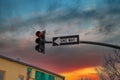 A traffic signal with a red light and a black and white one way sign with blue sky and majestic red clouds at sunset Royalty Free Stock Photo