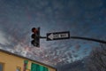 A traffic signal with a red light and a black and white one way sign with blue sky and majestic red clouds at sunset Royalty Free Stock Photo