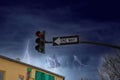 A traffic signal with a red light and a black and white one way sign with powerful storm clouds and lightning Royalty Free Stock Photo