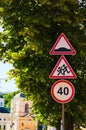 Traffic signs against green leaves linden tree at sunny morning. Warning Sign Children, Speed Limit Sign. Hump road sign post.