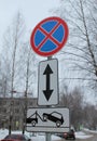 Traffic signs stop is prohibited, a tow truck is working, an arrow with two ends on a background of winter trees and a white sky Royalty Free Stock Photo