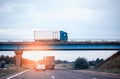 Traffic from trucks and cars on the road. A truck drives over a bridge against the backdrop of an evening sunset and blue sky. The