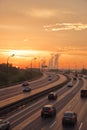 Traffic on a wide freeway against the backdrop of a sunset and a smoking power plant, July 2021 Royalty Free Stock Photo