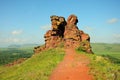 A trail along the top of the mountain to a high stone outlier against the backdrop of a picturesque valley