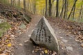 trail marker in the shape of a rock with arrows pointing each way