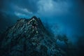 Trail runner in dark evening mountains, rocks. running in storm