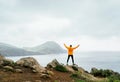 Trail runner man dressed orange waterproof jacket, running tights and shoes enjoying Atlantic ocean bay view on Ponta de Sao