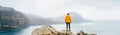 Trail runner man dressed orange waterproof jacket, running tights and shoes enjoying Atlantic ocean bay view on Ponta de Sao