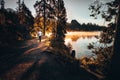 Trail runner in wild nature by lake, gold morning light in background