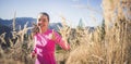 Trail running athlete exercising for fitness. Young woman smiling runner run in nature in mountains.