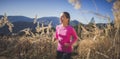 Trail running athlete exercising for fitness. Young woman smiling runner run in nature in mountains.