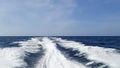 Sea wake trail behind a speed boat with waves, foam, bubbles on the ocean water surface with clear bright blue sky Royalty Free Stock Photo