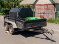 A trailer with a green box on the back of it parked on the side of the road Royalty Free Stock Photo