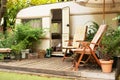 Trailer of mobile home stands in garden in camping. Backyard with RV house with garden furniture. Royalty Free Stock Photo