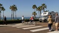 Trailer, people riding bikes, ped crossing zebra, waterfront road. Ocean beach palms, California USA Royalty Free Stock Photo