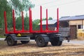 Trailer for transporting logs and planks with red fasteners and huge wheels