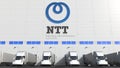 Electric trailer trucks at warehouse loading bay with NTT logo on the wall. Editorial 3D rendering Royalty Free Stock Photo