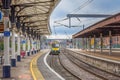 A train approaches a station beside a historic platform with columns and a canopy. Royalty Free Stock Photo