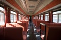 a train car with red seats and a long hallway between the two rows of seats is shown with red curtains and a black floor mat Royalty Free Stock Photo