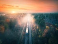 Train in colorful forest in fog at sunset in autumn. Aerial view Royalty Free Stock Photo