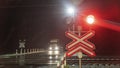 Train crossing gates closed at night. Train grade crossing with blinking or flashing lights while train is moving past
