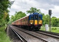 A train driver waves as his Class 455 South Western Railway passenger service train passes a signal in the Surrey countryside
