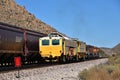 A train moves along a track while two yellow cars sit idle Royalty Free Stock Photo