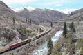 A train passes beside a river beneath California's Sierra Nevada mountains.