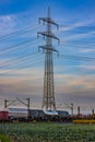 Train on a railroad line in the countryside in front of an electricity pylon Royalty Free Stock Photo