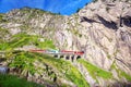 Train on the railway bridge Teufelsbrucke over Reuss river in St. Gotthard mountain range of Swiss Alps near Andermatt