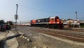 A Train with a Red and Blue Locomotive Crossing a Crowded Road