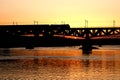 The train riding over the bridge over the river at sunset. Royalty Free Stock Photo