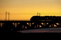 The train riding over the bridge over the river at sunset. Royalty Free Stock Photo