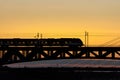 The train riding over the bridge over the river at sunset. Royalty Free Stock Photo