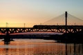 The train riding over the bridge over the river at sunset. Royalty Free Stock Photo